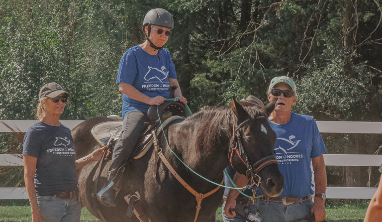 lady riding a horse with 2 volunteers