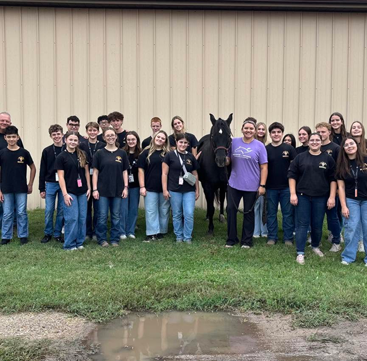 people wearing black shirts posing with Horse