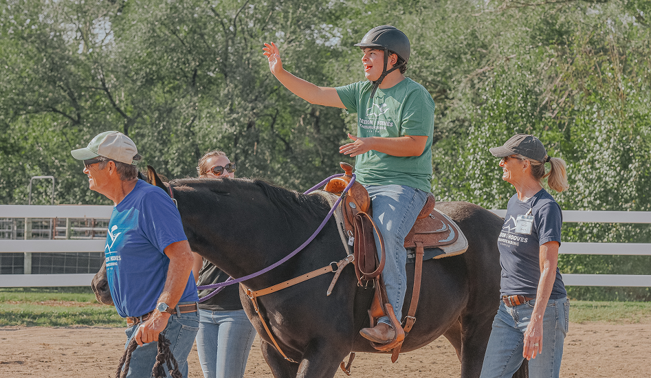 boy waving while riding a horse