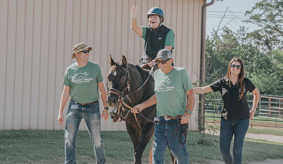 volunteers leading horse along with rider