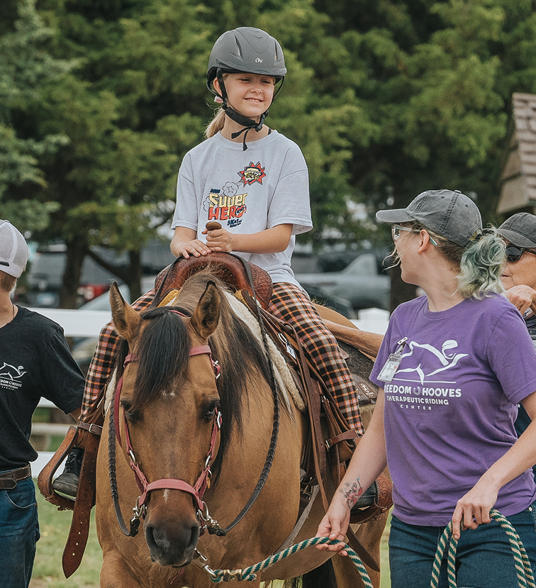 a girl is happily riding with volunteer lady