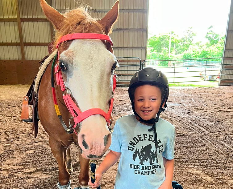 A boy with helmet leading the horse