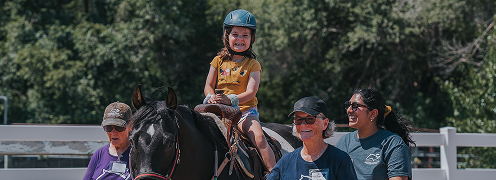 girl with helmet riding with volunteers